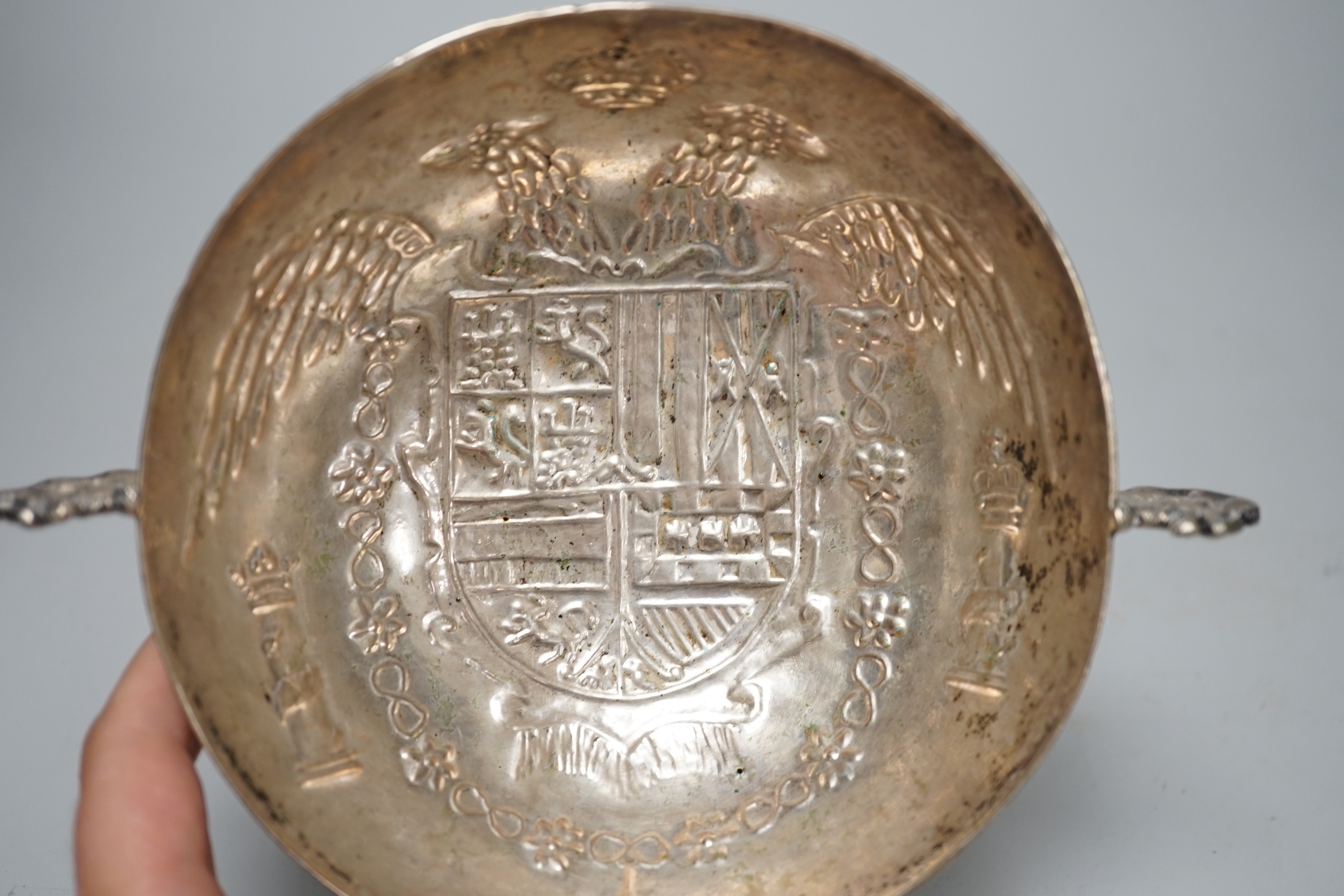 An antique continental white metal twin handled dish, embossed with a crest and double headed eagle, 19.3cm wide overall